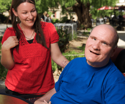 A man in a blue t-shirt sitting and a woman in a red shirt standing