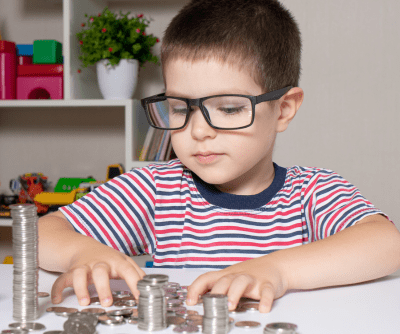 A boy in a striped t-shirt counts piles of coins