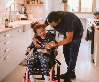 A man and a young girl in a kitchen. The young girl is in a wheelchair